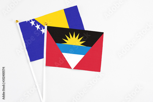 Free Download Antigua and Barbuda and Bosnia Herzegovina stick flags on white background. High quality fabric, miniature national flag. Peaceful global concept.White floor for copy space. - GFXLoad