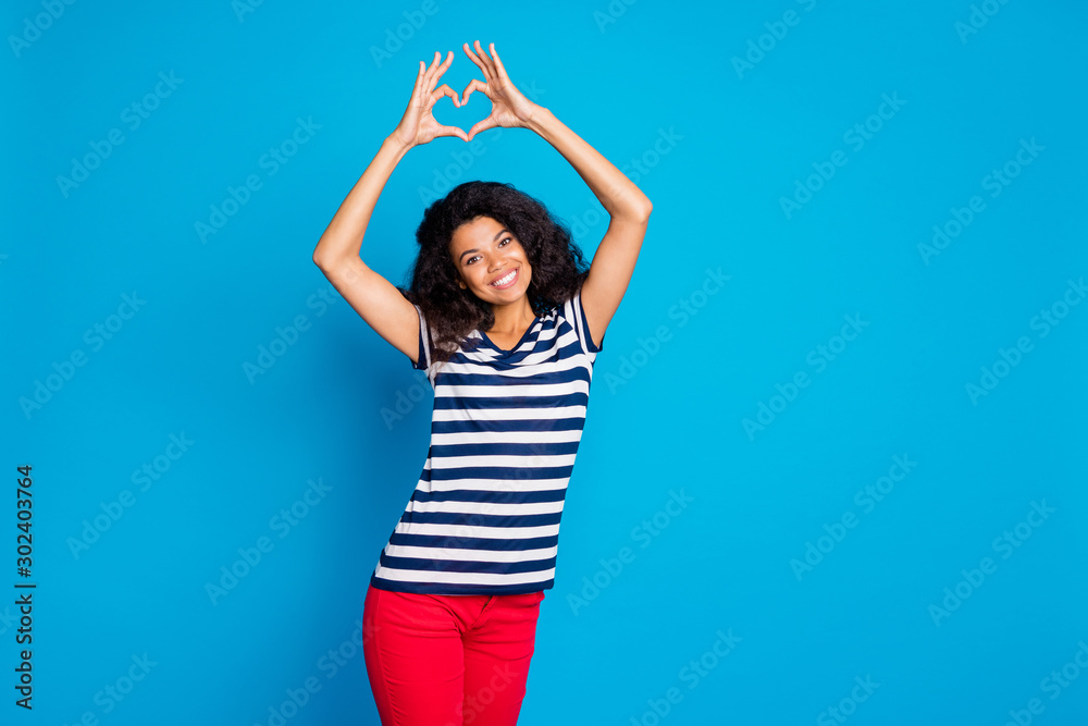 Photo of cheerful positive nice cute pretty sweet girlfriend smiling toothily beaming in striped t-shirt showing you heart shape sign formed with fingers isolated vivid blue color background Photo of cheerful positive nice cute pretty sweet girlfriend smiling toothily beaming in striped t-shirt showing you heart shape sign formed with fingers isolated vivid blue color background
