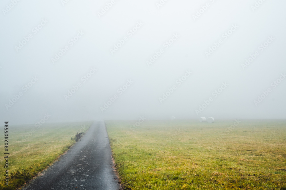 geteerter Feldweg zwischen zwei Feldern im Herbst im Nebel liegend geteerter Feldweg zwischen zwei Feldern im Herbst im Nebel liegend