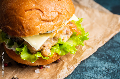 Fresh tasty burgers with roasted turkey cutlet, salad, cheese and different herbs on the rustic background. Selective focus. Shallow depth of field.