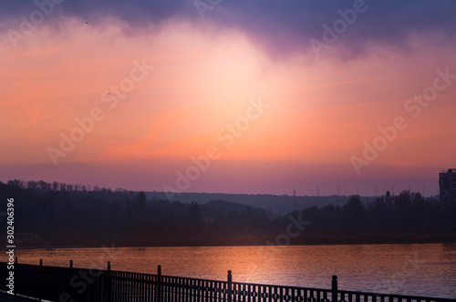 Unusual red sunset in a city park above the lake. © slava