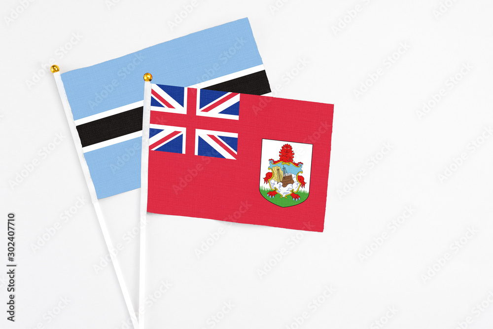 Fototapeta premium Bermuda and Botswana stick flags on white background. High quality fabric, miniature national flag. Peaceful global concept.White floor for copy space.