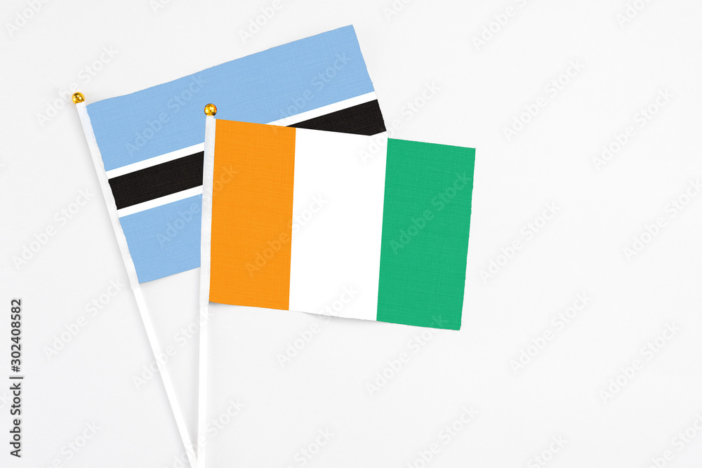 Cote D'Ivoire and Botswana stick flags on white background. High quality fabric, miniature national flag. Peaceful global concept.White floor for copy space.