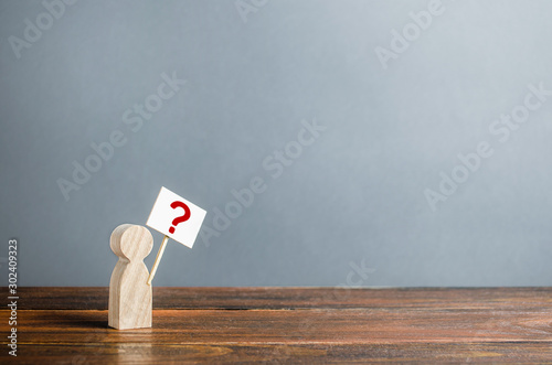 Man figurine with a poster and a question mark. Asking questions, searching for truth. Curiosity, desire to learn more and improve. Riddle mystery, investigation and research. Population Poll Survey