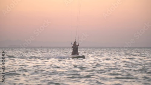 Colorful sunset on the background of a young woman kitesurfing in the sea