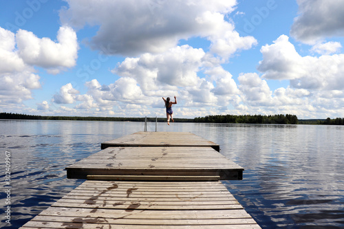 Obraz na plátně Girl jumping off the end of a pier at a lake in Finland