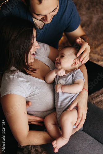 Baby with his parents playing on the bed. Happy family at home. Lifestyle cozy photos. Little boy 4 months old