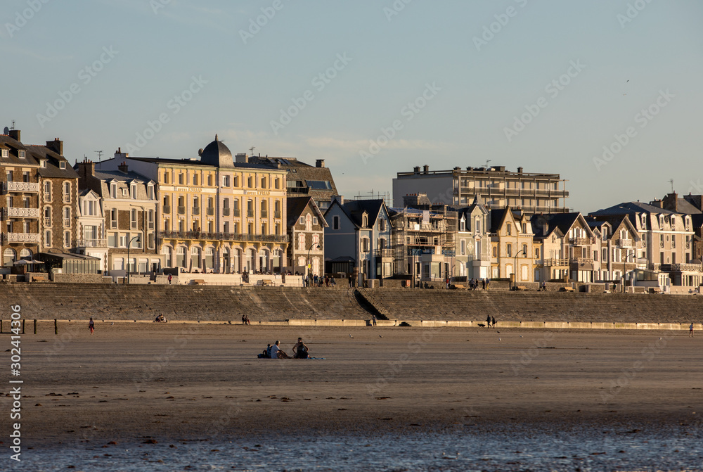 Naklejka premium Beach in the evening sun and buildings along the seafront promenade in Saint Malo. Brittany, France