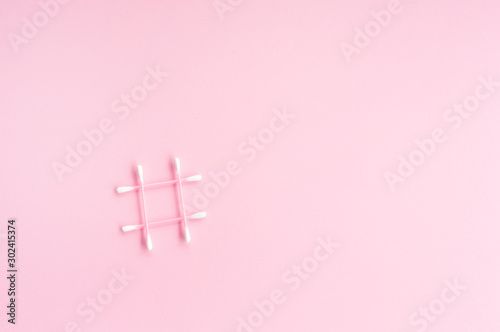 cotton swabs in the form of a hashtag on a pink background