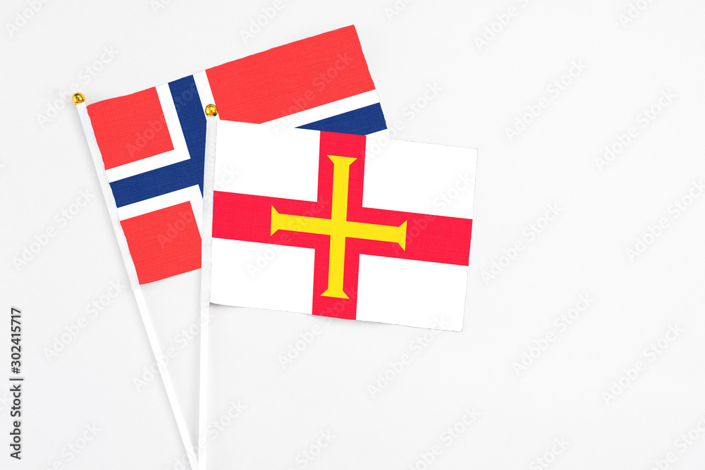 Guernsey and Bouvet Islands stick flags on white background. High quality fabric, miniature national flag. Peaceful global concept.White floor for copy space.