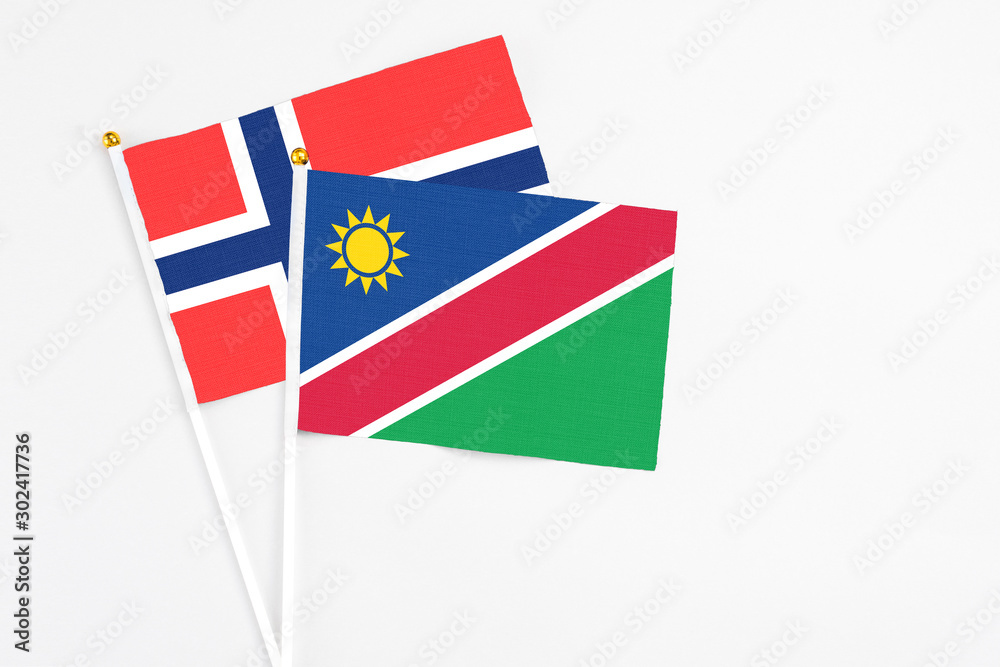 Fototapeta premium Namibia and Bouvet Islands stick flags on white background. High quality fabric, miniature national flag. Peaceful global concept.White floor for copy space.