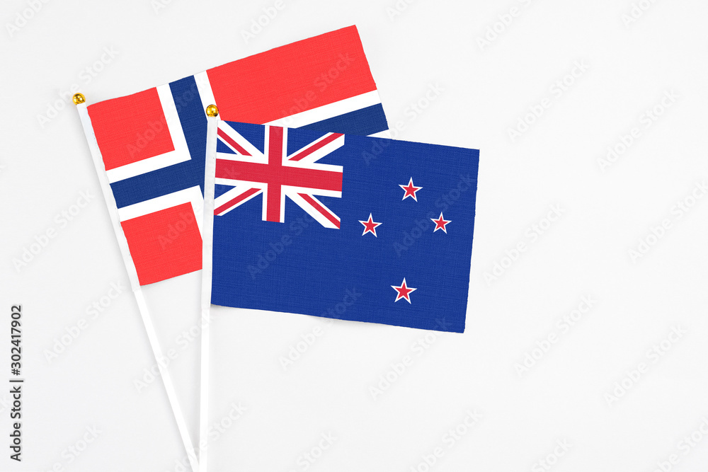 Fototapeta premium New Zealand and Bouvet Islands stick flags on white background. High quality fabric, miniature national flag. Peaceful global concept.White floor for copy space.