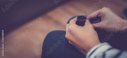Young lady hand hold a red wine cup in Holy Communion. Wine in simple plastic cup, with blank copy space