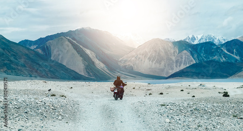 Tourist riding an adventure big bike motorcycle on tuff and bumpy road on rock mountain in clear beautiful lightning to explore the world, with copy space  photo