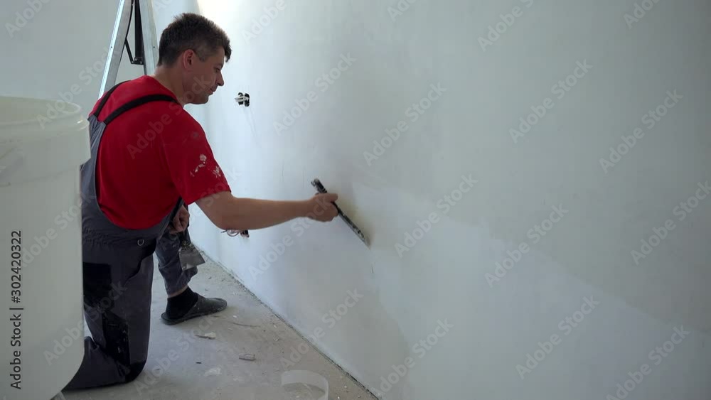 Handyman with spatula working on new apartment decorating works Handyman with spatula working on new apartment decorating works