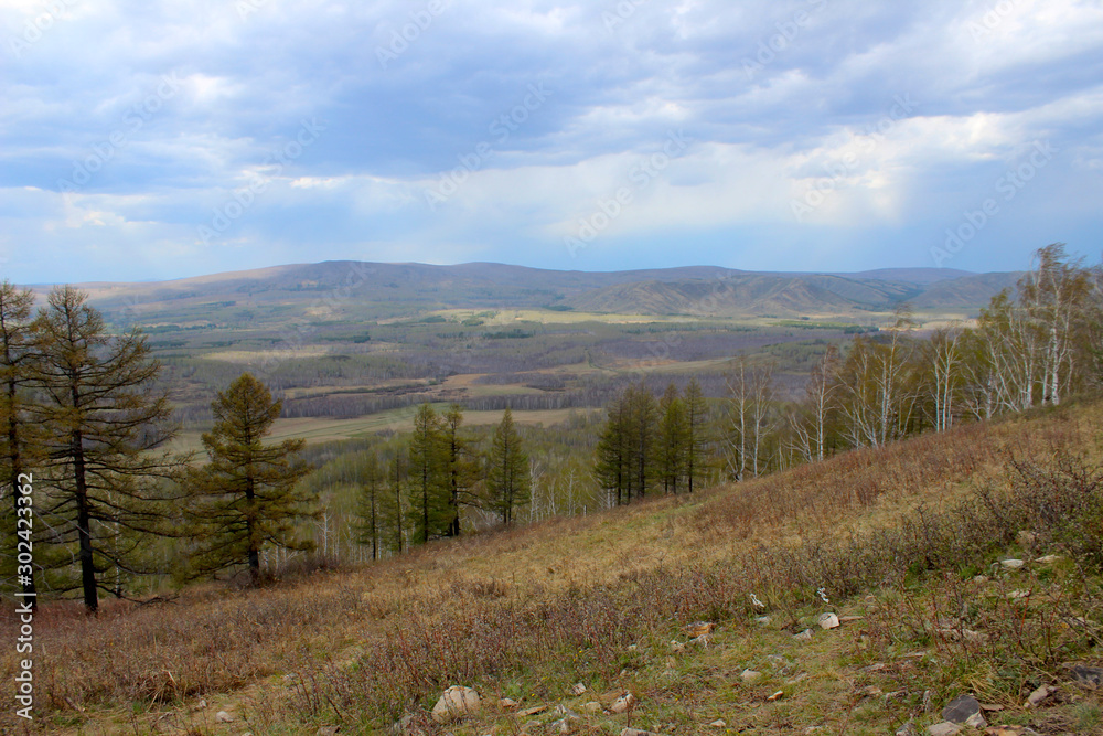 The view from the observation deck on Mount Aushkul shows a beautiful landscape of the area, mountains, forests and a blue sky with clouds. Spring landscape. Select focus The view from the observation deck on Mount Aushkul shows a beautiful landscape of the area, mountains, forests and a blue sky with clouds. Spring landscape. Select focus