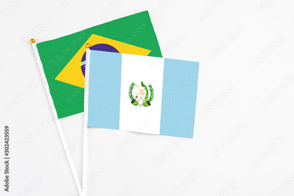 Guatemala and Brazil stick flags on white background. High quality fabric, miniature national flag. Peaceful global concept.White floor for copy space.