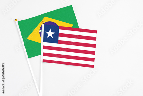 Liberia and Brazil stick flags on white background. High quality fabric, miniature national flag. Peaceful global concept.White floor for copy space.