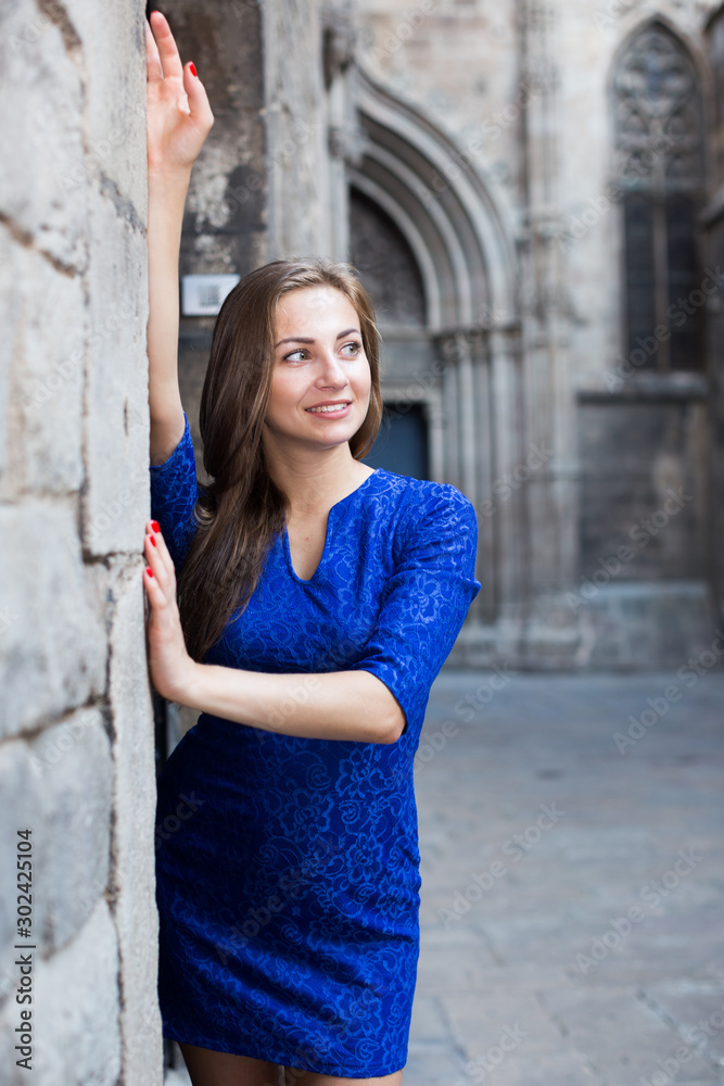 Young woman is posing in blue dress near old wall