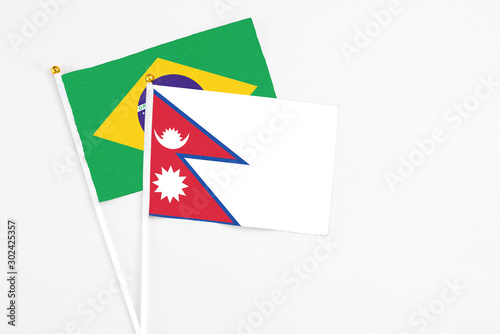 Nepal and Brazil stick flags on white background. High quality fabric, miniature national flag. Peaceful global concept.White floor for copy space.