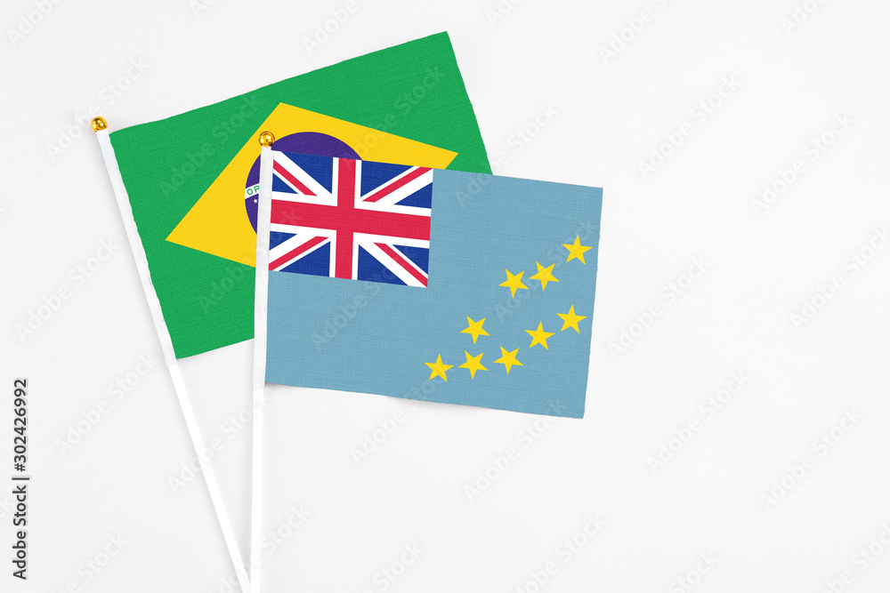 Fototapeta premium Tuvalu and Brazil stick flags on white background. High quality fabric, miniature national flag. Peaceful global concept.White floor for copy space.