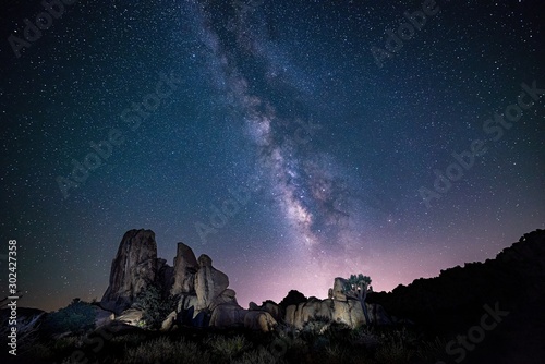 Beautiful shot of silhouettes of rocks under the purple sky full of stars - perfect wallpaper © Dmitrys/Wirestock