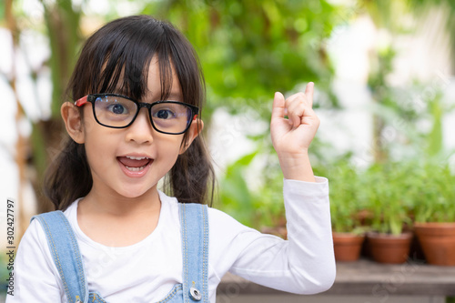 Attractive asian little girl is pointing to her plant in the pots and talking about how to planting with proud, concept of kid education for nature and ecology.