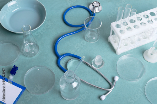 Stethoscope, lab glassware on the blue table.Concept of laboratory workplace