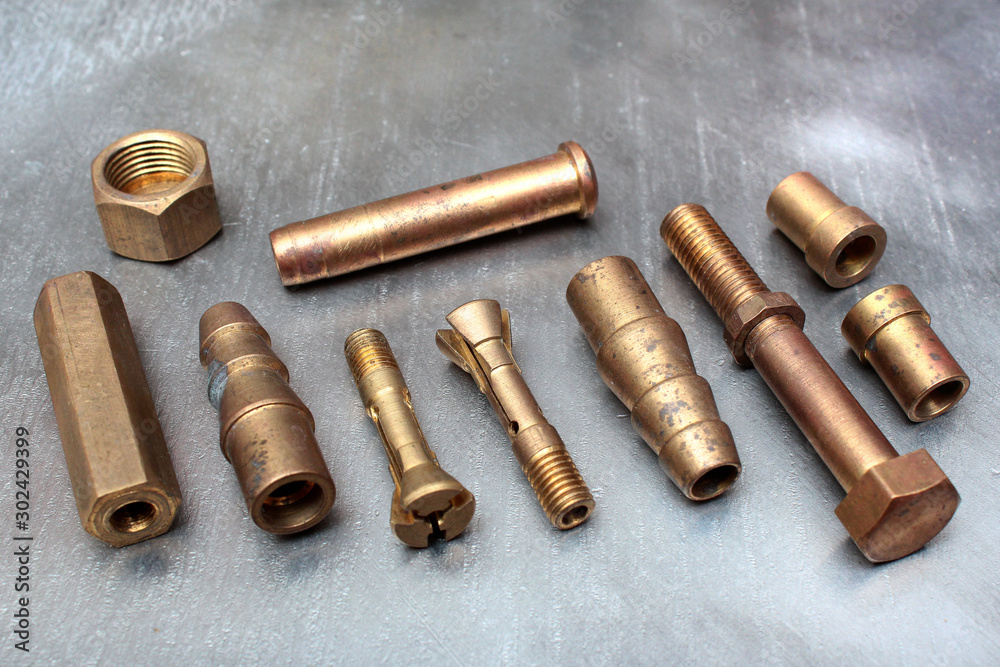 Brass bolts, screws and fittings on steel metal background