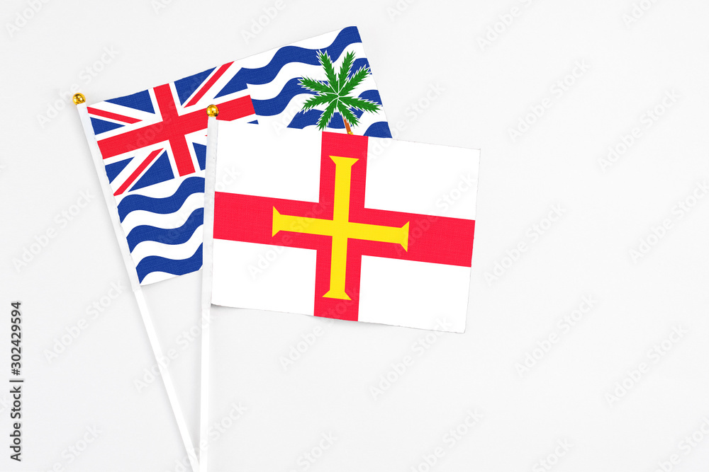Guernsey and British Indian Ocean Territory stick flags on white background. High quality fabric, miniature national flag. Peaceful global concept.White floor for copy space.