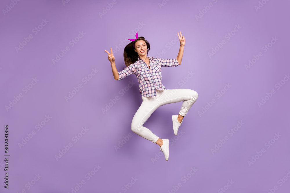 Full body photo of content youth girl enjoy spring weekends jump make v-signs wear casual style clothing sneakers isolated over violet color background Full body photo of content youth girl enjoy spring weekends jump make v-signs wear casual style clothing sneakers isolated over violet color background