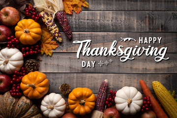Top view of  Autumn maple leaves with Pumpkin, apple, corn and red berries on old wooden background. Thanksgiving day concept.