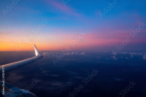 Aerial view from the plane on colorful sky before sunrise. Part of wing aircraft and turbine. Soft selective focus