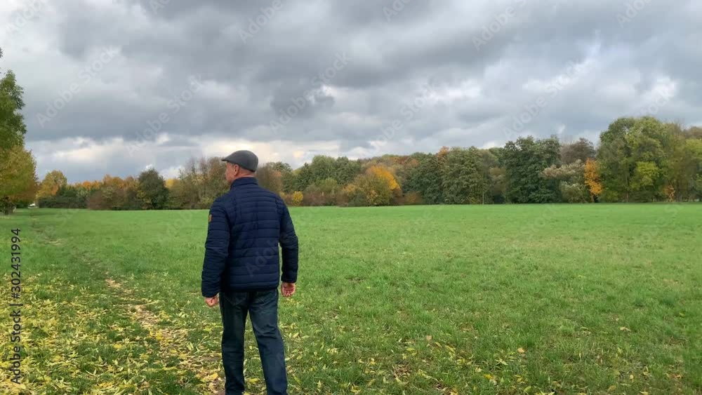 middle-aged man walks across the field in autumn, enjoys nature and good weather, concept of walking middle-aged man walks across the field in autumn, enjoys nature and good weather, concept of walking