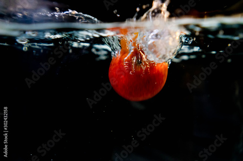 drop red apple in tank. water is splash on black background