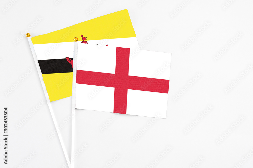England and Brunei stick flags on white background. High quality fabric, miniature national flag. Peaceful global concept.White floor for copy space.