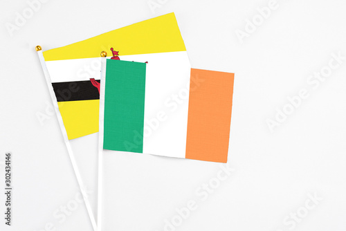 Ireland and Brunei stick flags on white background. High quality fabric, miniature national flag. Peaceful global concept.White floor for copy space.