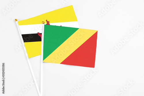 Republic Of The Congo and Brunei stick flags on white background. High quality fabric, miniature national flag. Peaceful global concept.White floor for copy space.