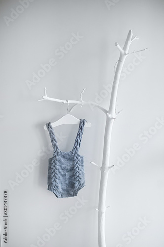 Knitted clothing made of sheep wool for young children who were just born. Hanging on a hanger on a deckboard tree on a white background. photo