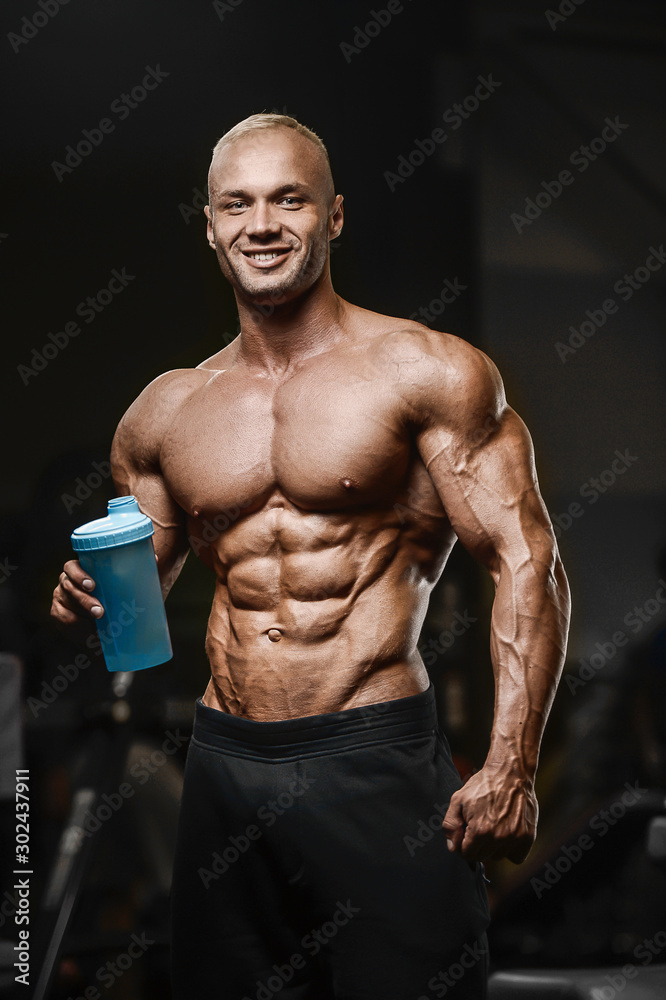 Sport muscular fitness man drinking water after workout cross fitness and bodybuilding concept gym background abs muscle exercises in gym naked torso fitness concept ..