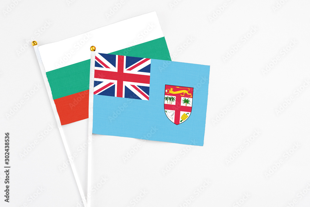 Fototapeta premium Fiji and Bulgaria stick flags on white background. High quality fabric, miniature national flag. Peaceful global concept.White floor for copy space.