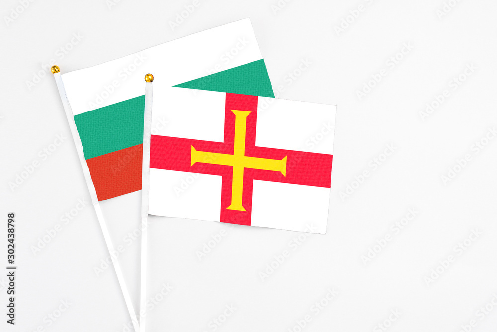 Guernsey and Bulgaria stick flags on white background. High quality fabric, miniature national flag. Peaceful global concept.White floor for copy space.