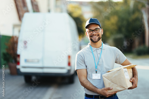 Portrait of young happy courier with packages for a delivery.