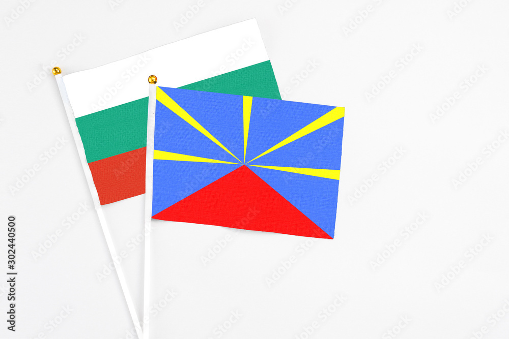 Reunion and Bulgaria stick flags on white background. High quality fabric, miniature national flag. Peaceful global concept.White floor for copy space.