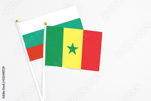 Senegal and Bulgaria stick flags on white background. High quality fabric, miniature national flag. Peaceful global concept.White floor for copy space.