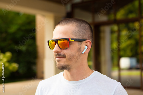 Adult man in sunglasses with wireless earphones