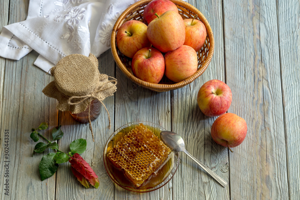 The jar with honey and apples in a wicker basket close-up The jar with honey and apples in a wicker basket close-up