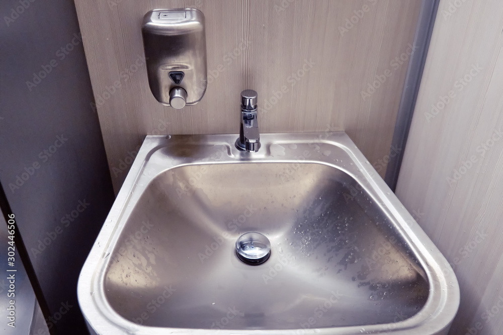 New modern metal sink with soap dispenser in public toilet New modern metal sink with soap dispenser in public toilet