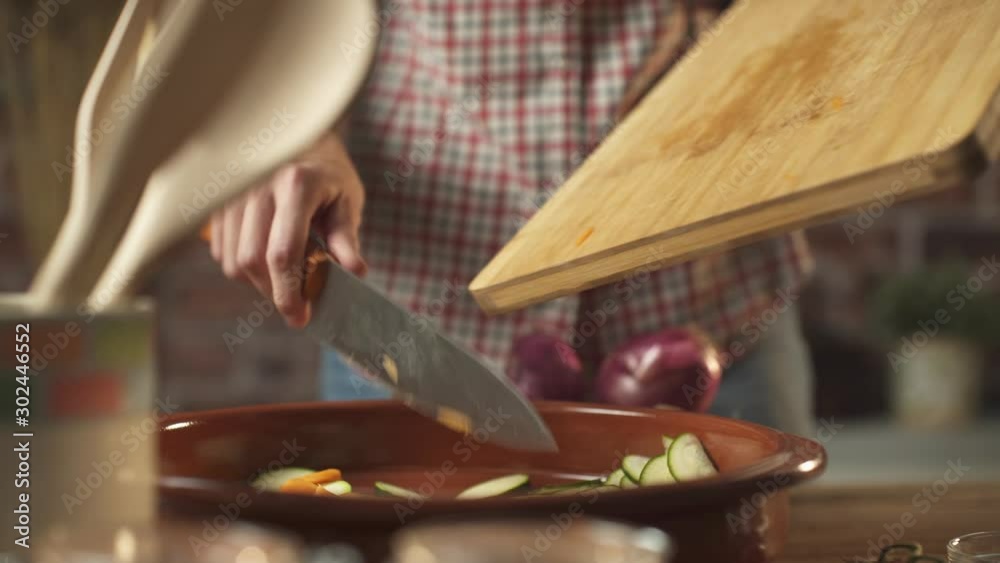 Woman pouring chopped vegetables in a pot