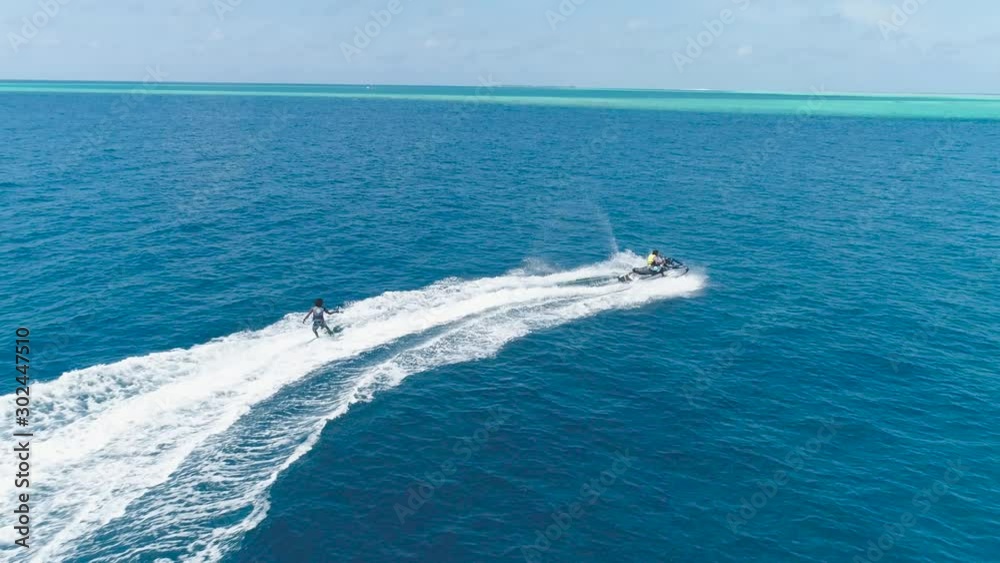 Drone tracking Slow motion shot Over Man Riding Jet Ski At Tropical Paradise Exotic Island with blue and turquoise ocean sea view. Adventure Concept for Tourist Attraction at Beach Vacation at Summer Drone tracking Slow motion shot Over Man Riding Jet Ski At Tropical Paradise Exotic Island with blue and turquoise ocean sea view. Adventure Concept for Tourist Attraction at Beach Vacation at Summer